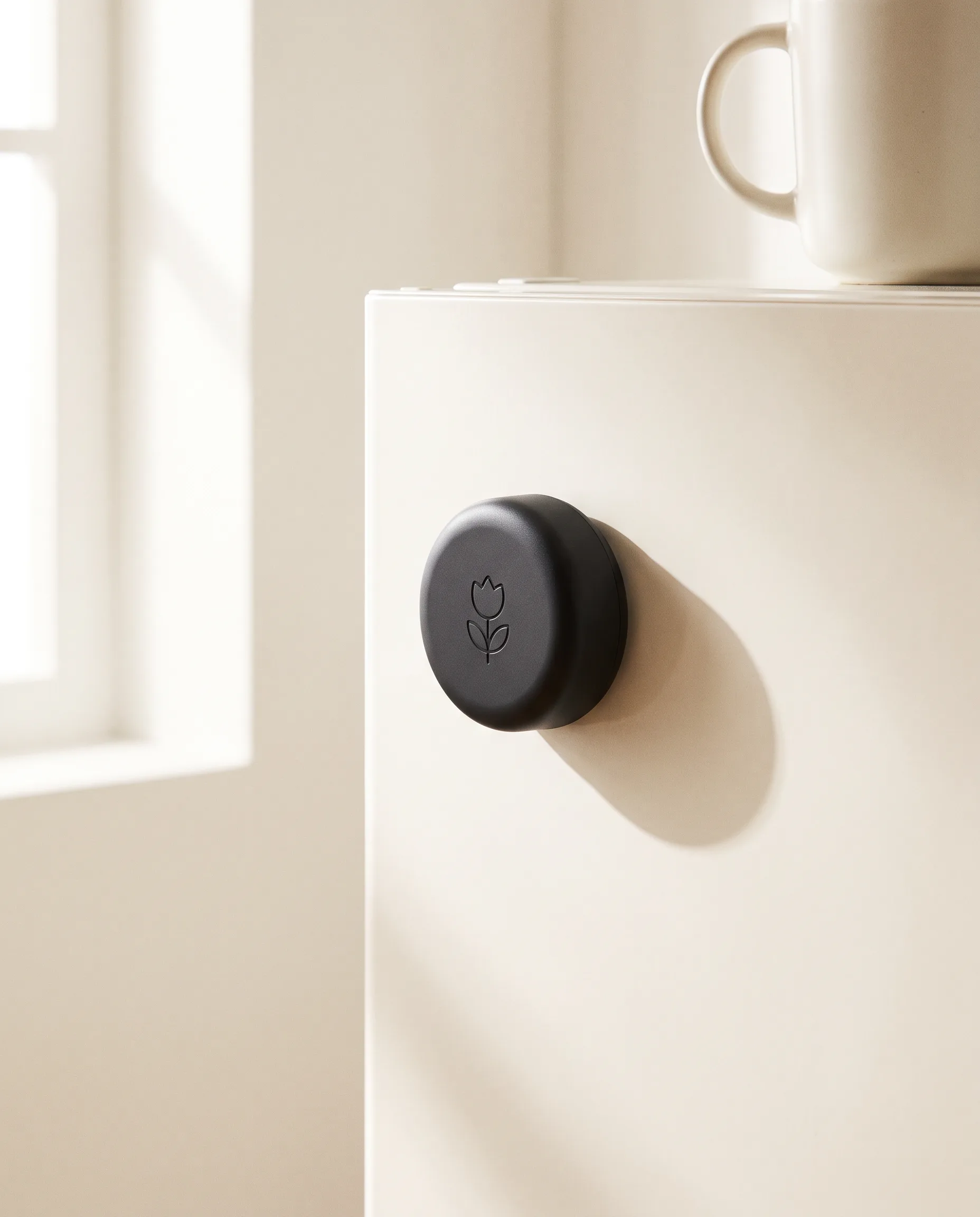 A round black Bloom Pod stuck to a white fridge door